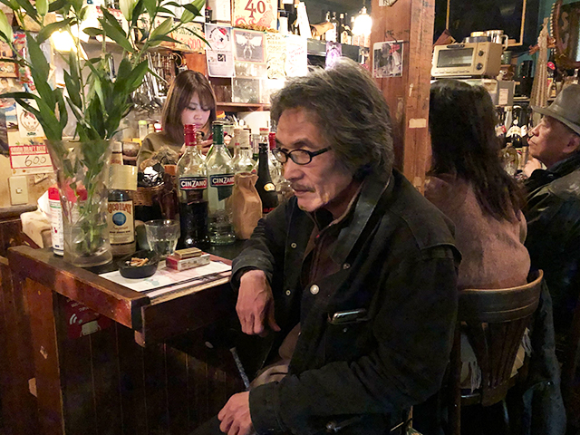 2018年12月20日、下北沢のバー「ネヴァーネヴァーランド」でカウンターに座った仁尾さん=吉野太一郎撮影